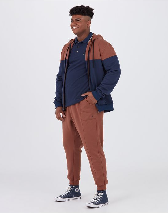 A guy with a pear shaped body wearing a hoodie and joggers standing for a photo.