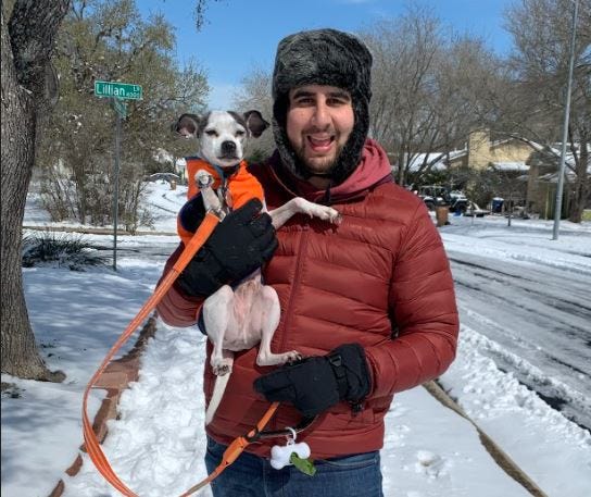My husband is carrying our dog who had a tough time walking through the snow with his bare paws.