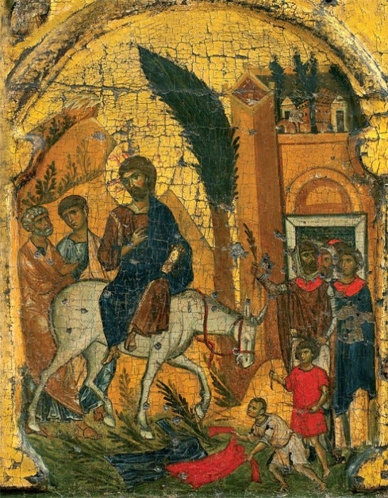 An icon, paint on wood. Jesus on a donkey entering Jerusalem. His disciples stand alongside his path as he enters the city.