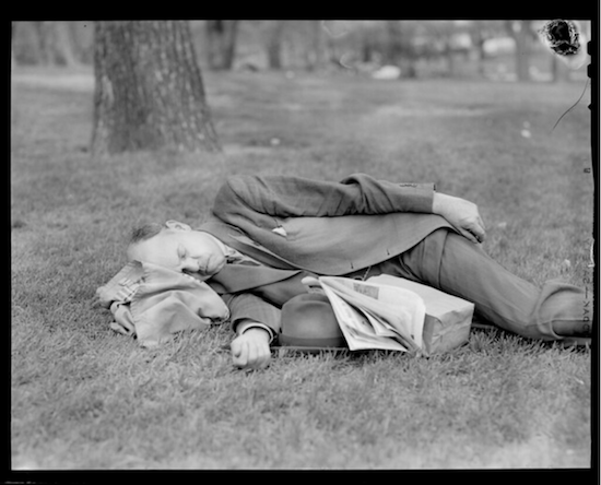 image of a man in a business suit asleep in a park