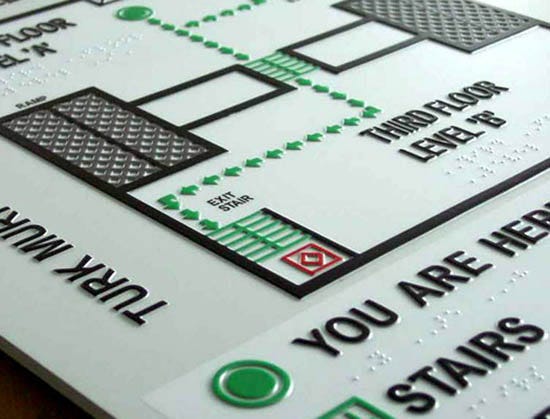 A map with tactile engraving of stairs, walls and direction. Also, the text is displayed in both tactile and braille.