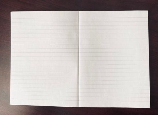 A blank lined notebook open on a table.