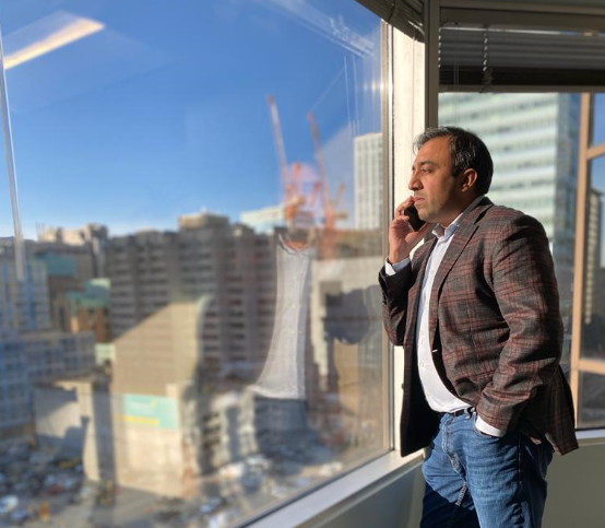 Photo of Minister Rasheed looking out to downtown Toronto from the main offices of the Ontario Digital Service while taking a stakeholder call.