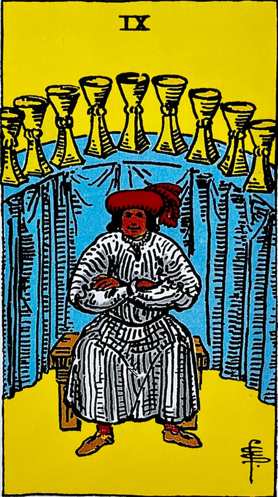 The Nine of Cups — A man sits on a bench in front of an altar showing nin cups on a blue cloth.