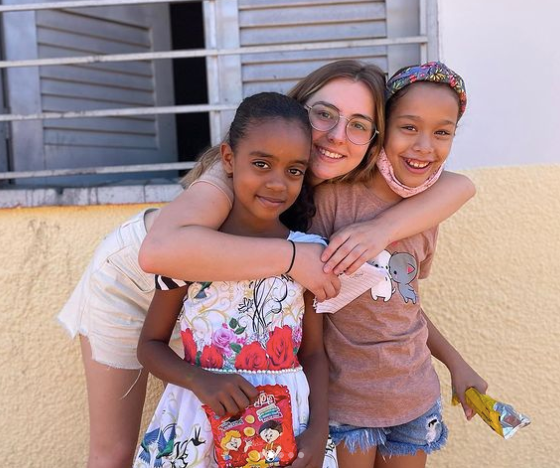 A volunteer embraces two young people in Brazil.