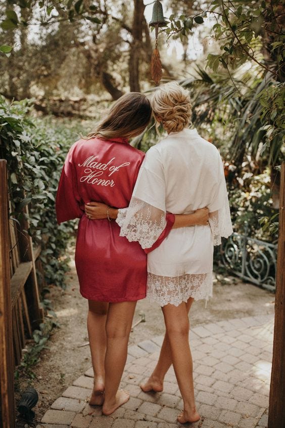A picture of a Maid of Honour and the Bride standing arms in arms