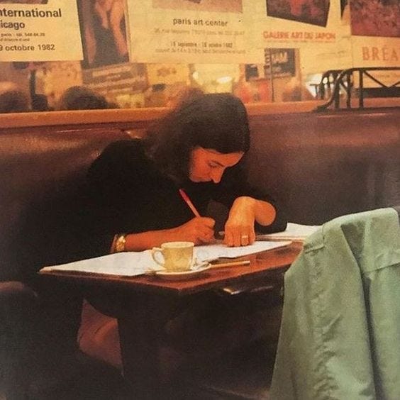A woman is writing intently at a cafe.