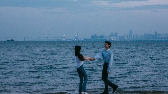 Sang Zhi pulling Duan Jiaxu by his hand on the beach shore