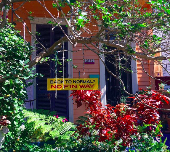 Sign hanging from a tree in front of a house in New Orleans that says “Back to Normal? No F’in Way”