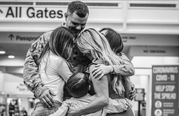 Christie, her two daughters and son, hugging, their husband/father after he returns home from his latest deployment.