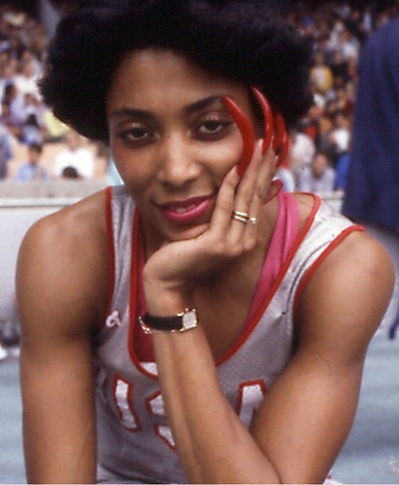 Florence Flo Jo Griffith-Joyner stares at the camera, smiling and showing off her colorful long, red nails. She has an Afro