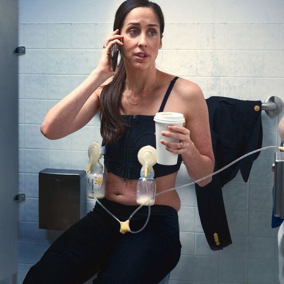 Woman wearing a breast pump bra while on the phone, drinking coffee, in the bathroom at work