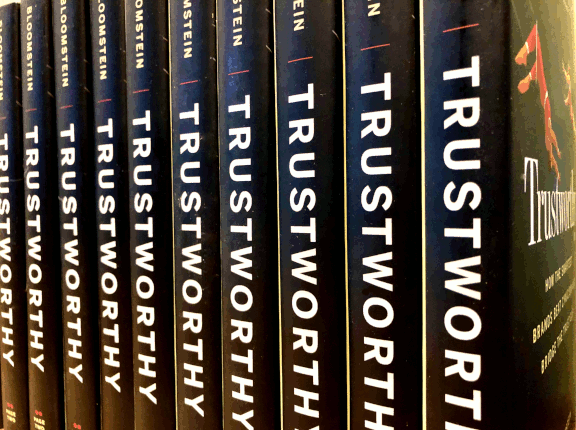 Row of hardcover copies of Trustworthy on a shelf.