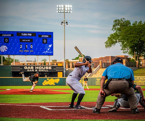 Pitcher firing fastball to a batter. Ump behind catcher.