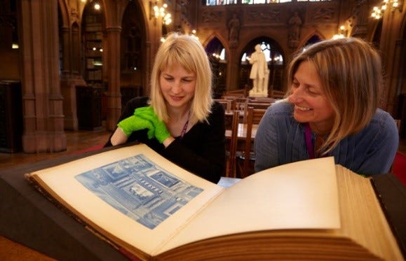 Two curators looking at an album of cyanotypes