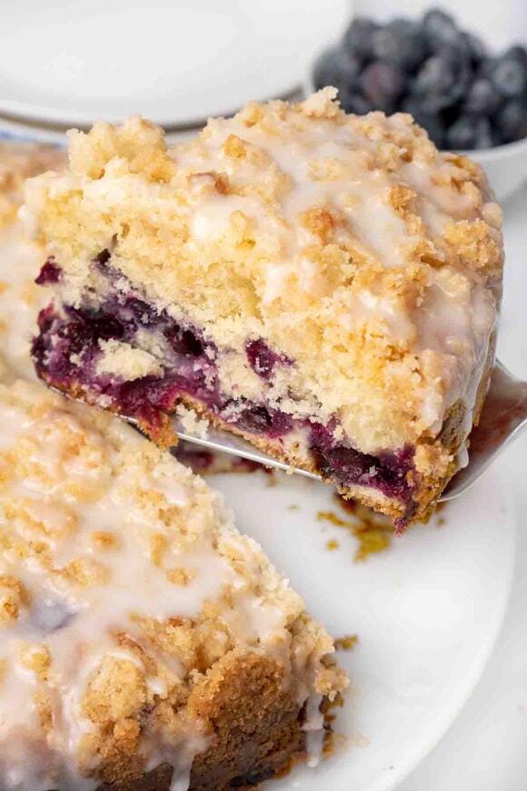 slice of blueberry coffee cake being lifted out of the whole cake with a spatula