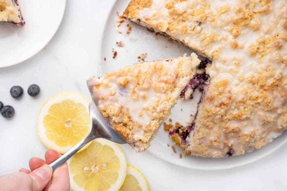 slice of blueberry coffee cake being taken out of the cake with a spatula