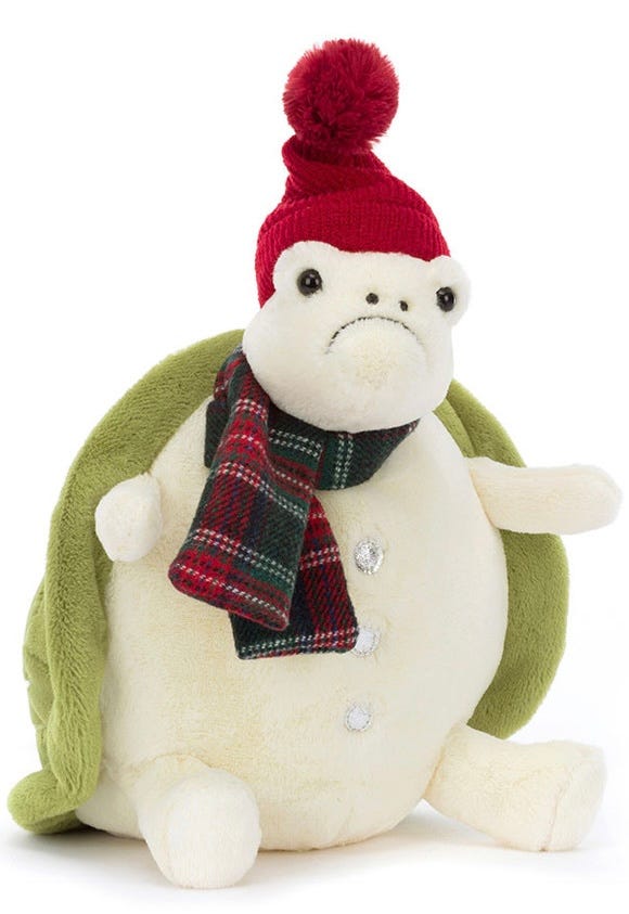 White and green plushie turtle with a tartan scarf, a red hat and a frown