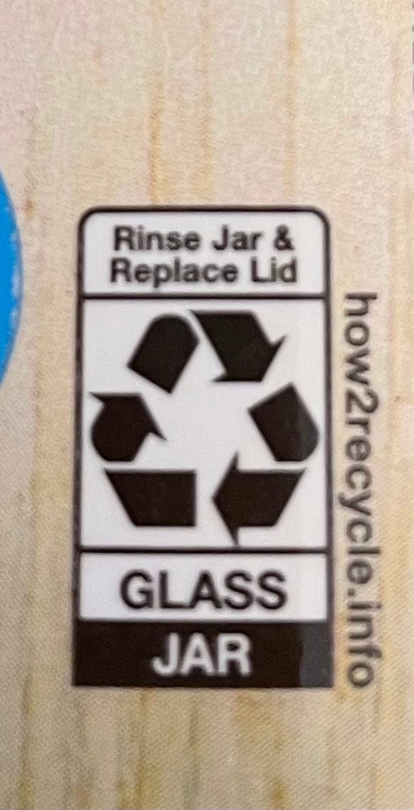 The recycle symbol with the instructions, “Rinse Jar & Replace lid. Glass Jar.”