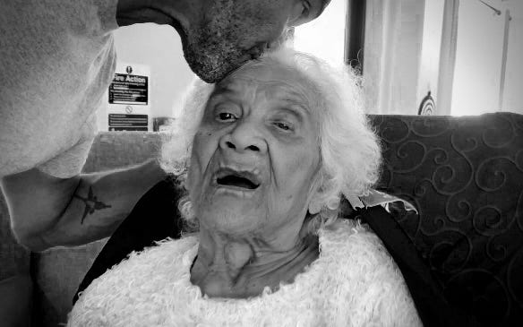 The author kissing his elderly mother goodbye on her forehead.