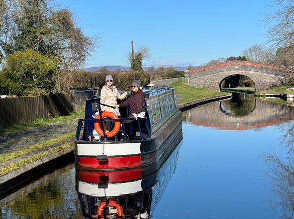 Crew on stern of narrowboat on a chilly, 

mirror still canal