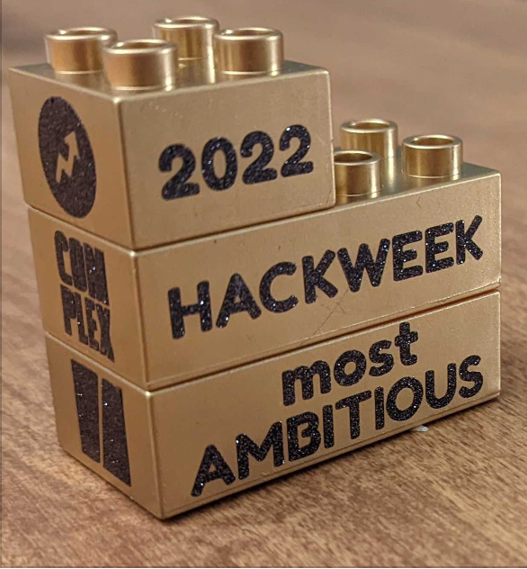 Hack week trophy: three gold spray painted lego bricks that say “2022 Hack Week Most Ambitious”