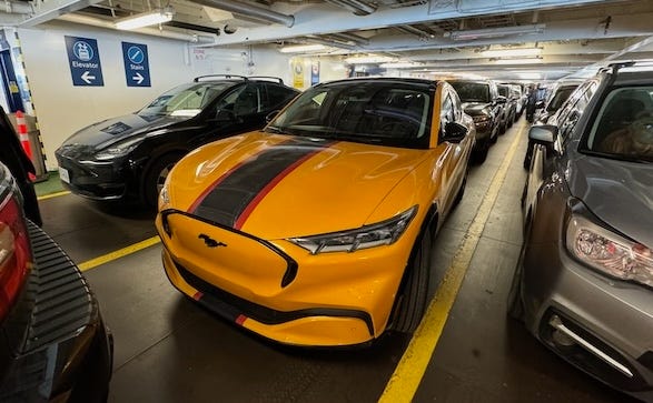 Rows of cars in a car ferry, a Tesla Model 3 and a Mustang Mach-E in front