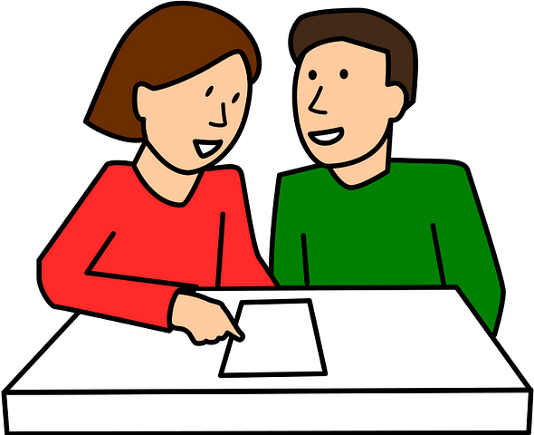 female presenting individual wearing red pointing at document on a table, engaged in conversation with a male presenting individual wearing green