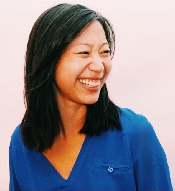 Color photo of Tiffany Yu, an Asian-American woman in a bright blue shirt, looking off to the side and smiling.