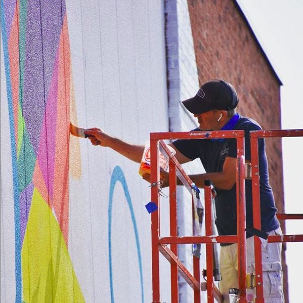 Jason Watts on lift painting mural in Suwanee, Georgia