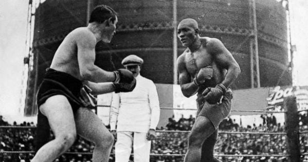 A black-and-white photograph of a white boxer and a Black boxer fighting in a ring.