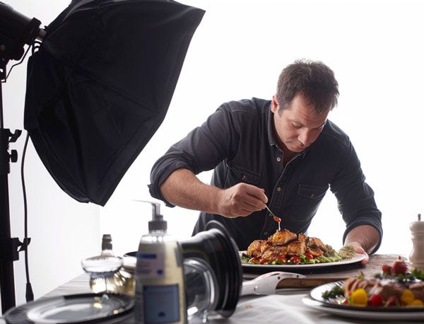 A professional food photographer applying small touches to his food.