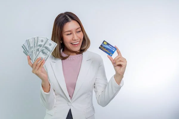 A business woman smiling while holding US Dollars and a credit card