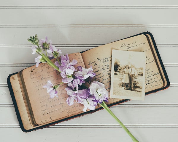 an open notebook with flower and an old photo kept on it.