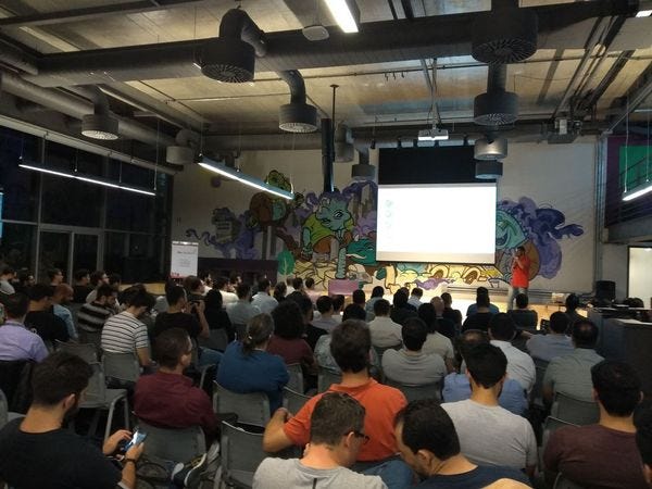 Foto com aproximadamente 100 pessoas assistindo uma apresentação no AWS User Group São Paulo