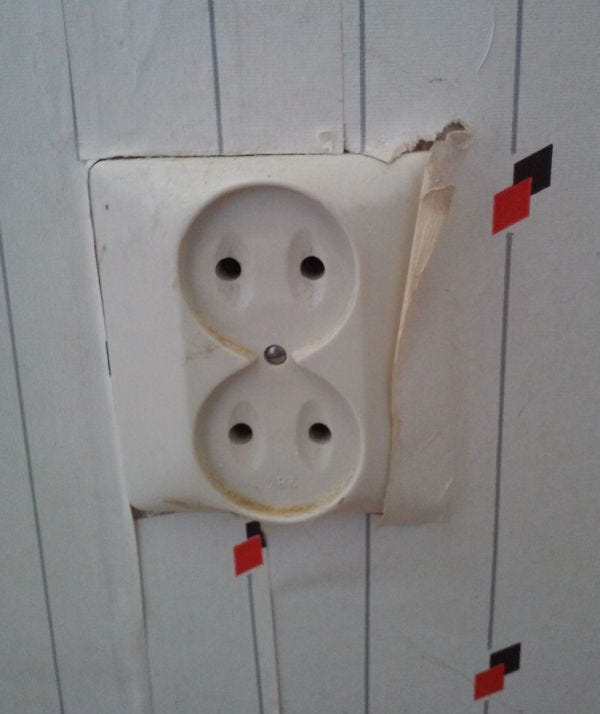 rough wallpapering behind a wall power socket outlet