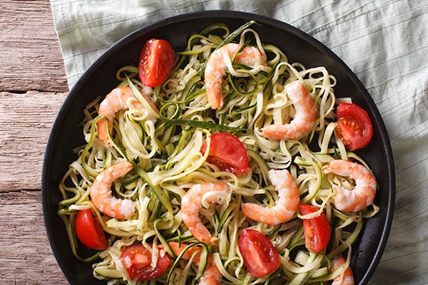 Dietary food: zucchini pasta with shrimp and tomato on a plate close-up. horizontal view from above