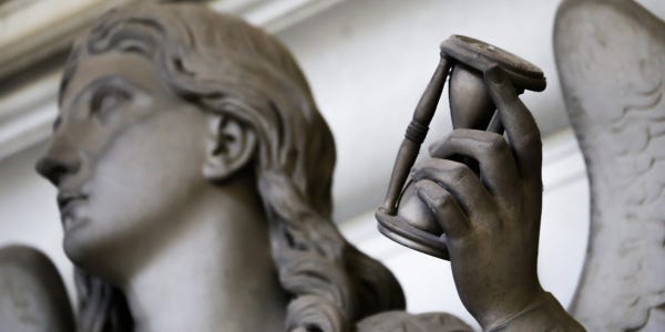 statue with wings holding hourglass