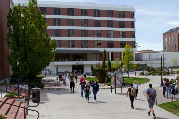 Photo of College Students Walking on Campus In Front Of Business School Building