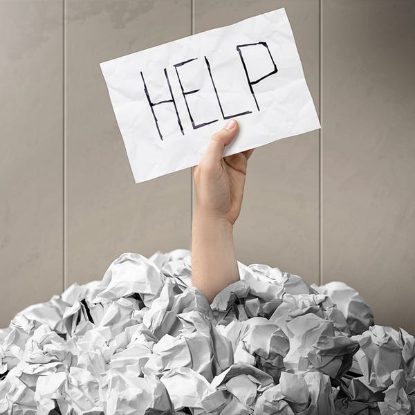 Image of an arm covered in balls of paper, with a hand coming out with a sign saying Help