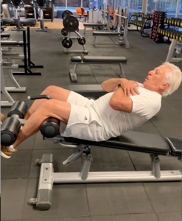 homem idoso faz exercício abdominal numa academia de ginástica