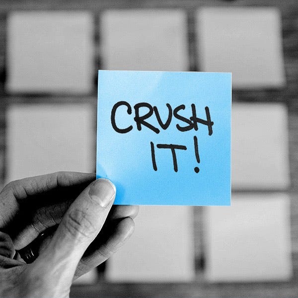 Hand holding a post-it note with the words “CRUSH IT!” on it.