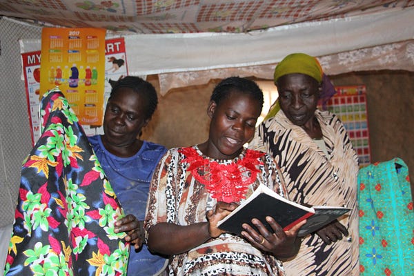 Village Enterprise business owners mark down income and spending in a book