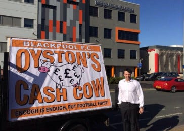 Karl Oyston, the chairman of Blackpool FC, [posing by a poster protesting](http://2244480991.jpg) against the way that the Oyston family run the club.