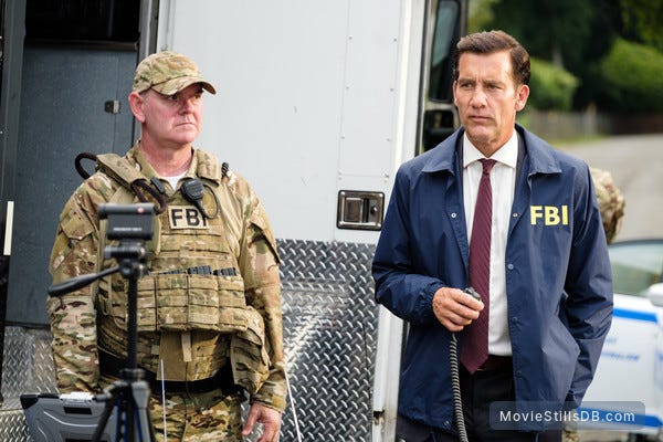 Clive Owen holds a radio and stands next to an FBI agent in The Informer
