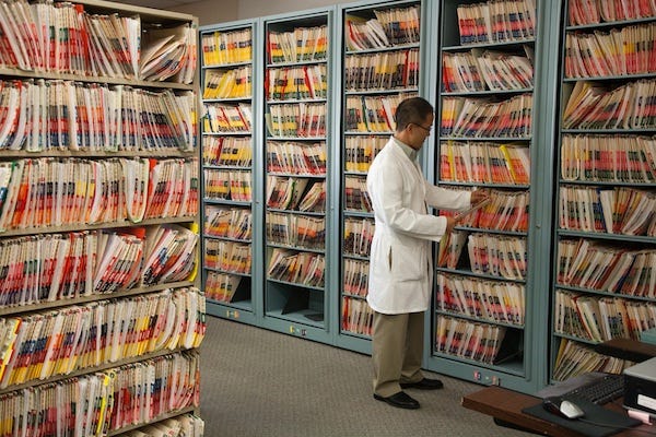 Man in lab coat with health files