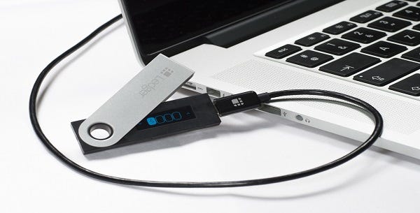Ledger device connected to a laptop via USB cable