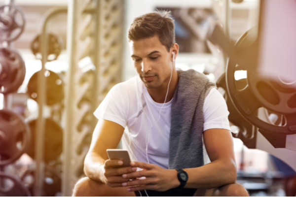 man-at-gym-working-out-with-mobile-fitness-program