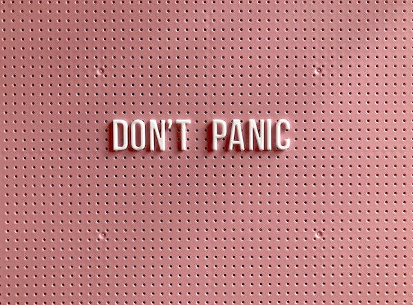 white letters on a pink pegboard spelling “don’t panic”
