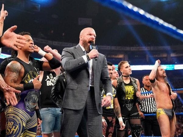 Triple H in the ring, surrounded by his NXT kids